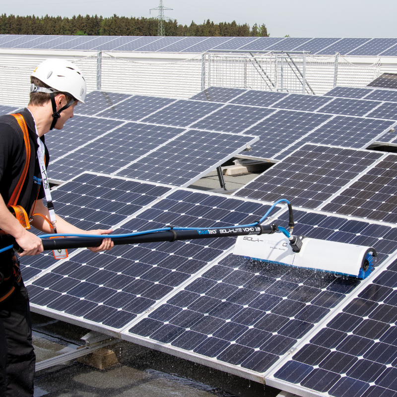 Worker cleaning a solar panel array with Kränzle equipment